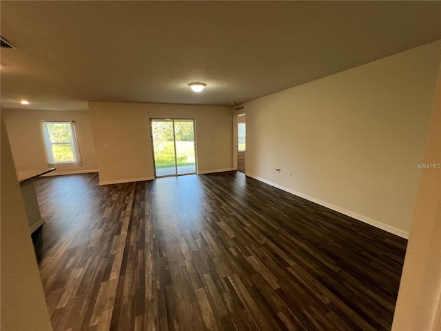 spare room with a textured ceiling and dark hardwood / wood-style floors