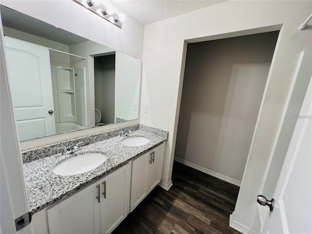 bathroom with vanity, wood-type flooring, a textured ceiling, and walk in shower