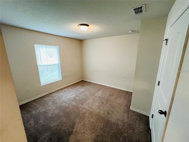 empty room with dark carpet and a textured ceiling