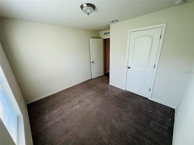 unfurnished bedroom with dark colored carpet and a closet