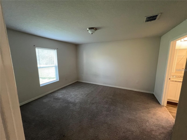 carpeted empty room featuring a textured ceiling