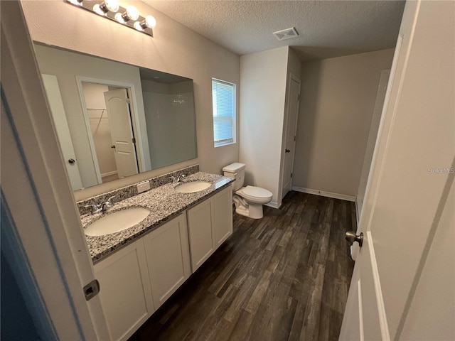 bathroom featuring vanity, hardwood / wood-style floors, a textured ceiling, and toilet