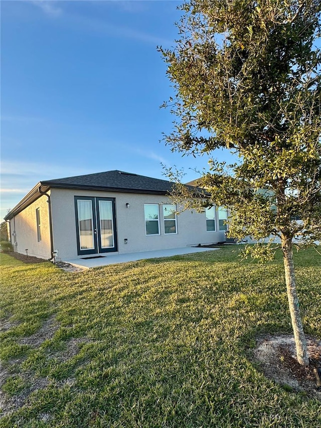 rear view of house featuring a lawn and a patio