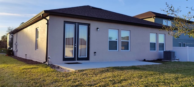 back of property featuring a lawn, central air condition unit, and a patio