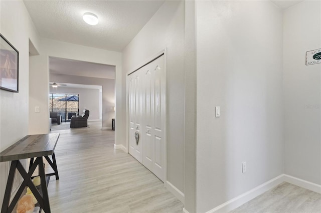 hallway with a textured ceiling and light wood-type flooring