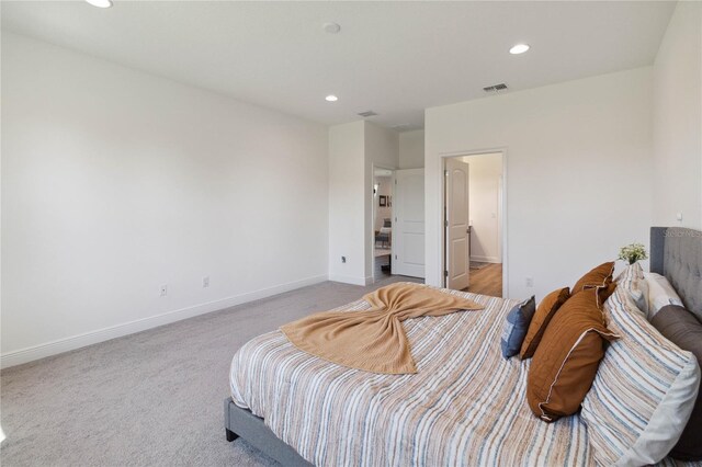 bedroom featuring connected bathroom and light colored carpet