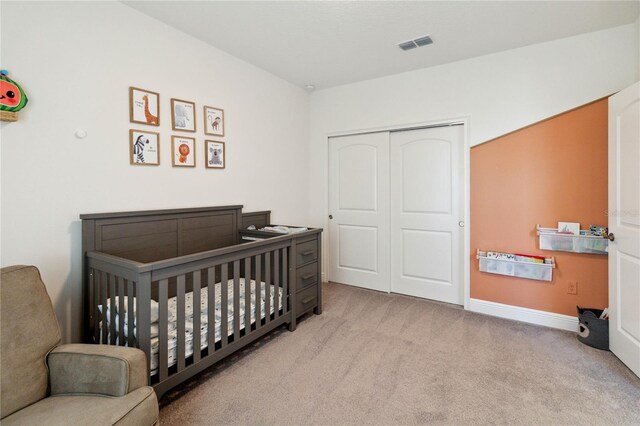 carpeted bedroom featuring a crib and a closet