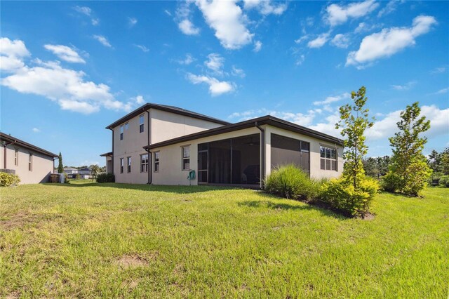 back of property with a sunroom and a lawn