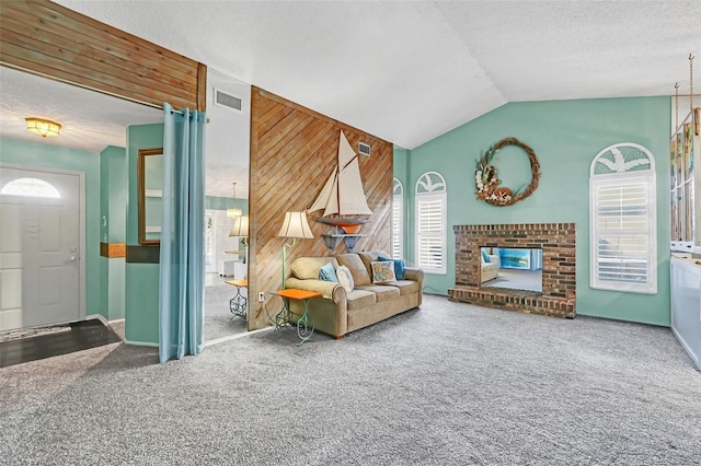 carpeted living room featuring a textured ceiling, wooden walls, vaulted ceiling, and a brick fireplace