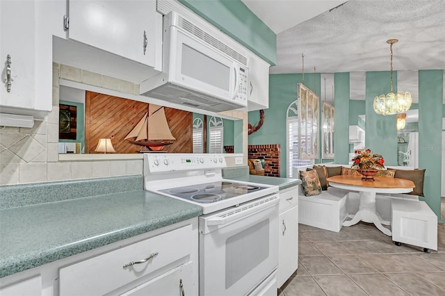 kitchen featuring white appliances, wooden walls, pendant lighting, an inviting chandelier, and white cabinets