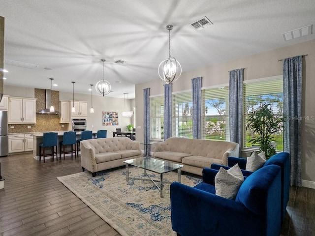 living room with a textured ceiling, dark wood-type flooring, and a chandelier