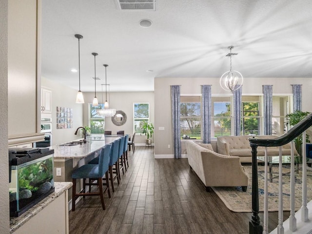 living room with dark hardwood / wood-style flooring, sink, and a chandelier