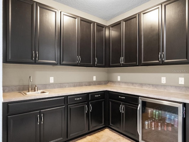 kitchen with a textured ceiling, light tile patterned floors, sink, and wine cooler