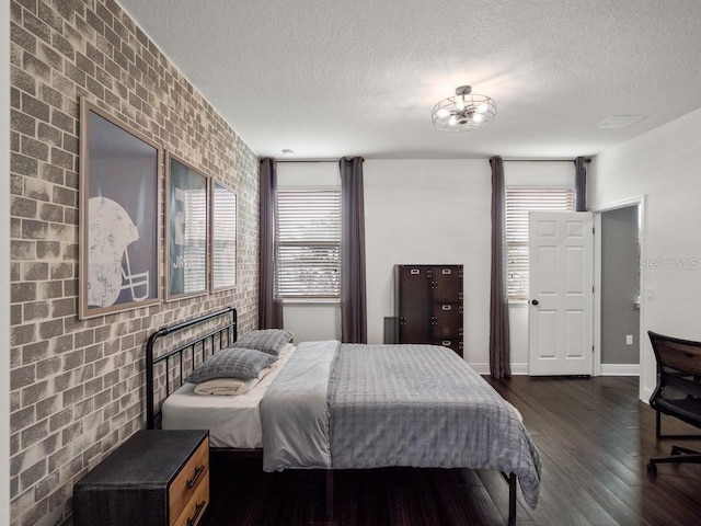 bedroom with a textured ceiling, multiple windows, and brick wall