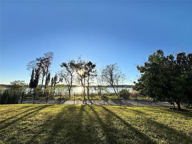 surrounding community with a water view and a lawn