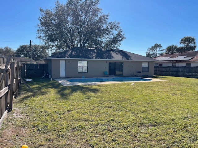 rear view of property with a yard, a fenced in pool, and a patio