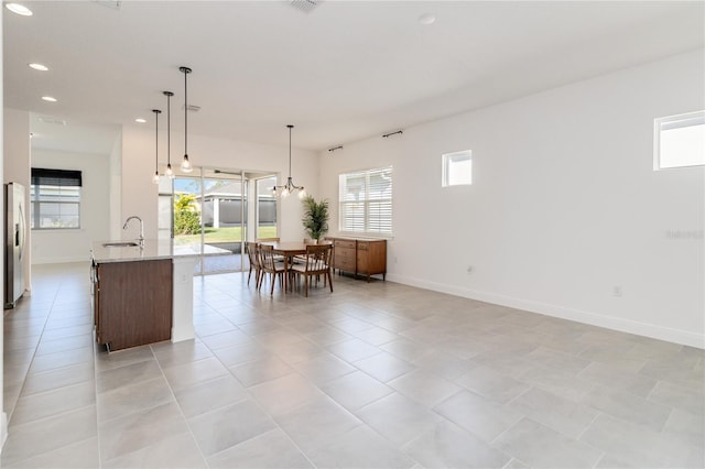 kitchen featuring an island with sink, decorative light fixtures, plenty of natural light, and sink