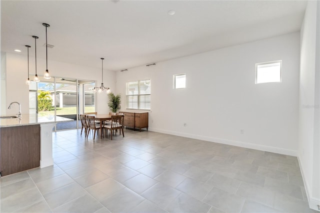 tiled dining room featuring a wealth of natural light, a notable chandelier, and sink