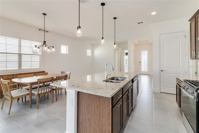 kitchen with appliances with stainless steel finishes, an island with sink, decorative light fixtures, and sink