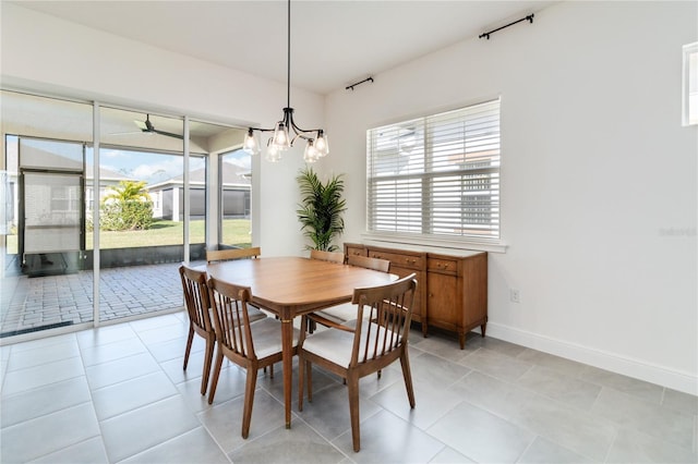 tiled dining area with ceiling fan with notable chandelier and a wealth of natural light