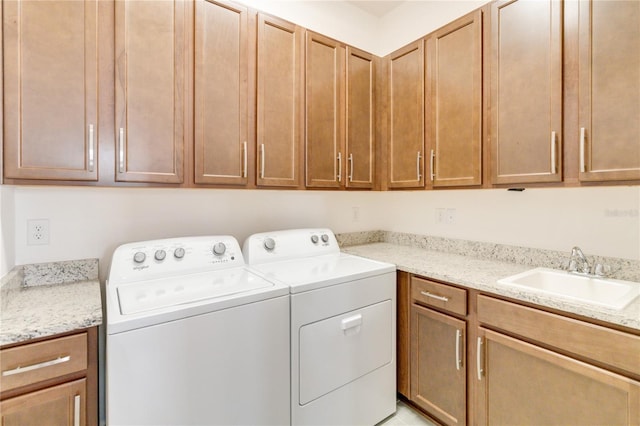 clothes washing area featuring cabinets, washer and clothes dryer, and sink