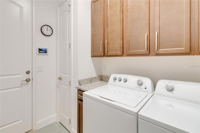 clothes washing area featuring cabinets, light tile patterned floors, and washer and dryer