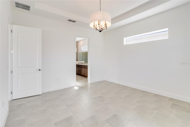 tiled spare room with a chandelier