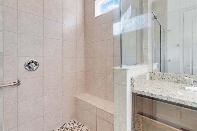 bathroom featuring tiled shower and vanity