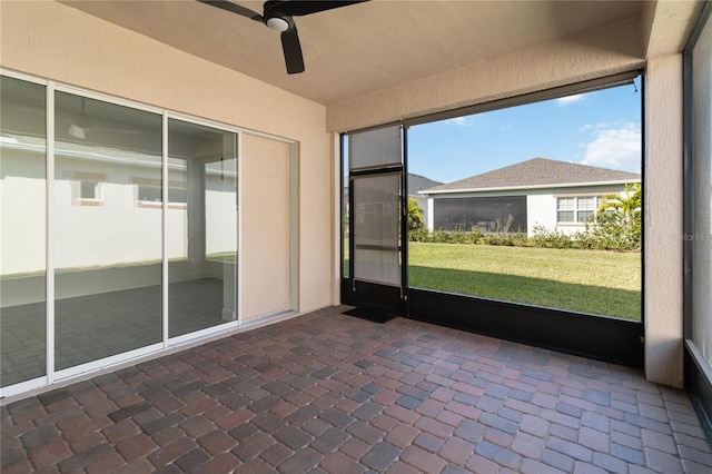 unfurnished sunroom featuring ceiling fan