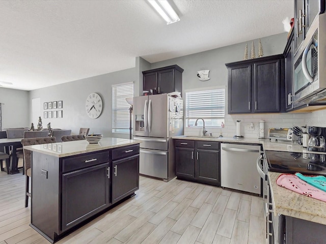 kitchen with tasteful backsplash, sink, a center island, light hardwood / wood-style floors, and stainless steel appliances