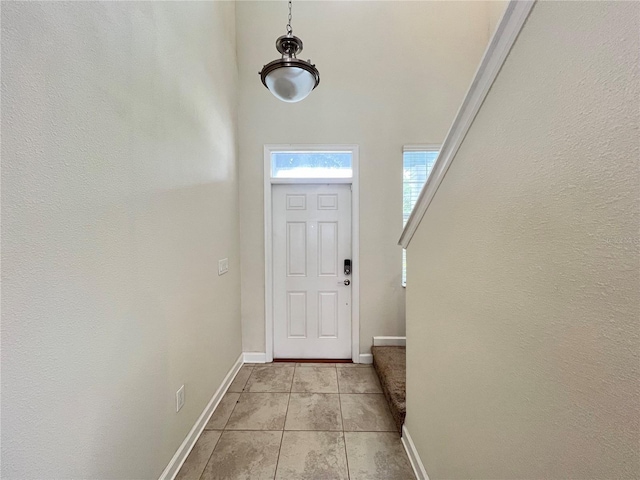 doorway to outside featuring light tile patterned floors and a towering ceiling