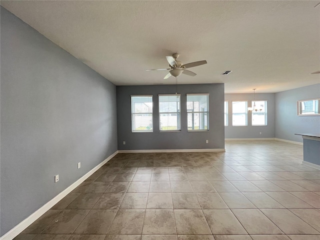 spare room with ceiling fan with notable chandelier, light tile patterned flooring, and a textured ceiling