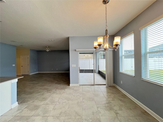 unfurnished dining area with light tile patterned floors, ceiling fan with notable chandelier, and a healthy amount of sunlight