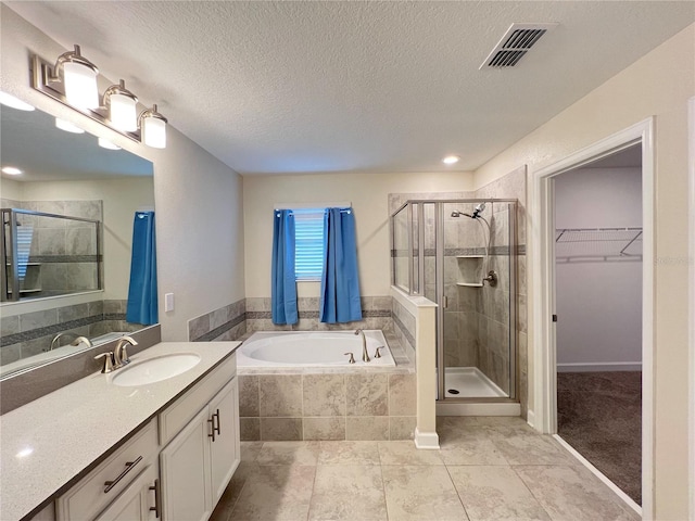 bathroom with tile patterned floors, vanity, a textured ceiling, and shower with separate bathtub