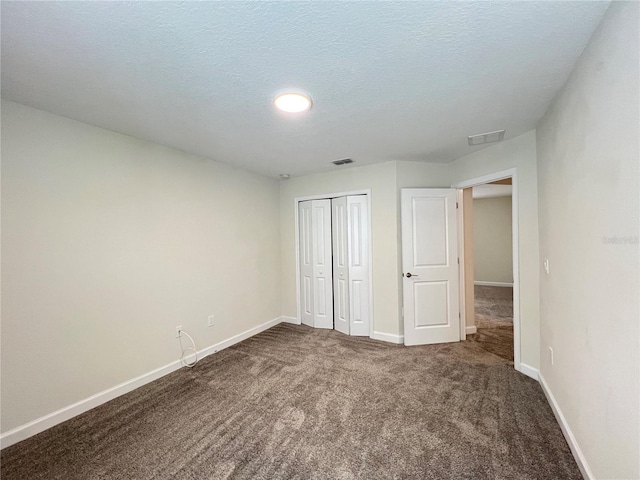 unfurnished bedroom with a textured ceiling, carpet floors, and a closet