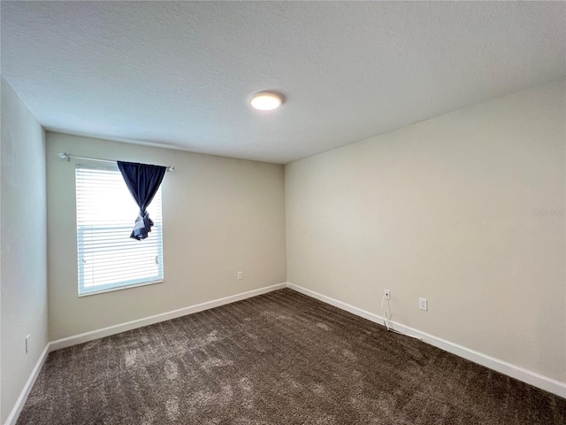 spare room featuring dark colored carpet and a textured ceiling