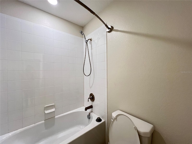 bathroom with tiled shower / bath combo and toilet