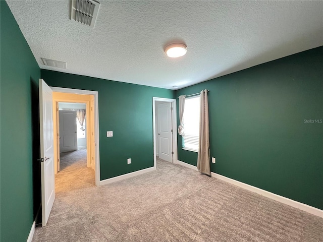 unfurnished bedroom with light carpet and a textured ceiling