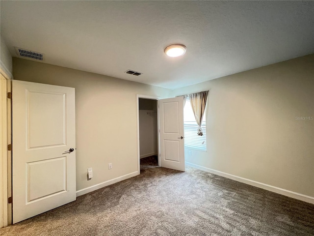 unfurnished bedroom featuring dark carpet, a spacious closet, and a closet