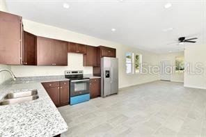 kitchen with dark brown cabinets, ceiling fan, stainless steel electric stove, sink, and white refrigerator with ice dispenser