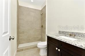 bathroom featuring vanity, toilet, and tiled shower