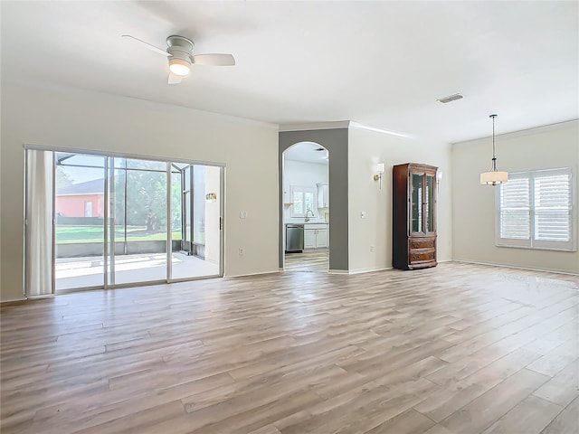 unfurnished living room with a wealth of natural light, light wood-type flooring, ceiling fan, and sink