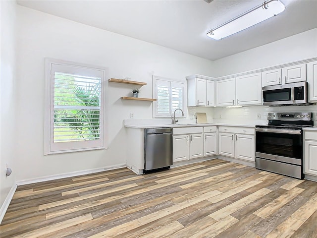 kitchen with white cabinets, appliances with stainless steel finishes, light hardwood / wood-style floors, and sink