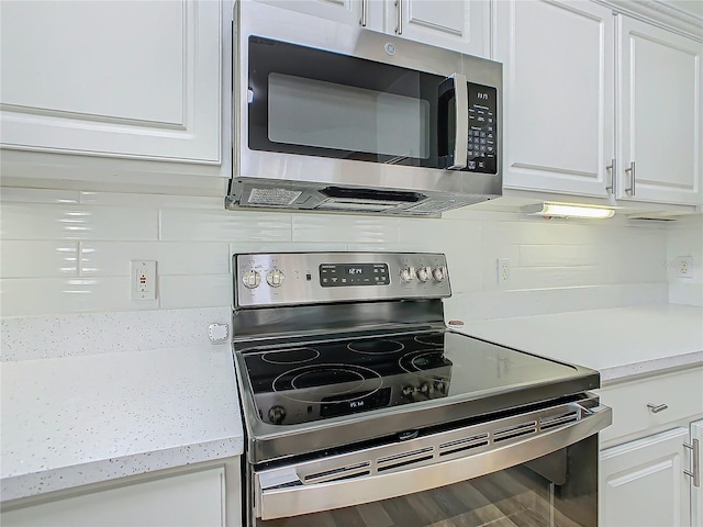 kitchen featuring backsplash, hardwood / wood-style floors, white cabinets, and stainless steel appliances