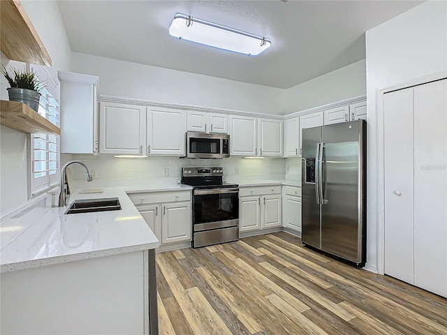 kitchen featuring sink, light hardwood / wood-style flooring, decorative backsplash, white cabinetry, and stainless steel appliances