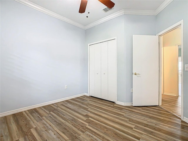 unfurnished bedroom with wood-type flooring, a closet, ceiling fan, and crown molding