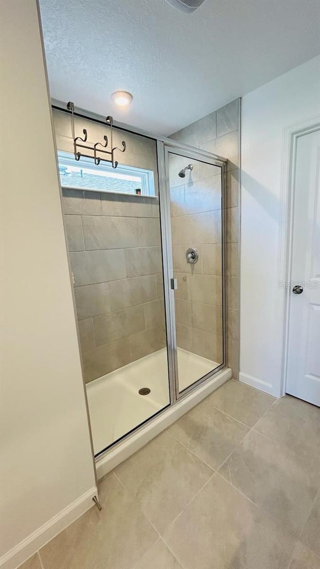 bathroom featuring a textured ceiling, tile patterned flooring, and an enclosed shower