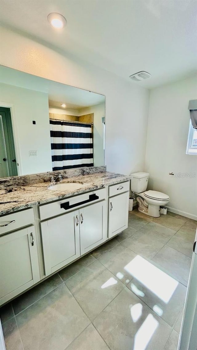 bathroom with a shower with curtain, vanity, toilet, and tile patterned floors