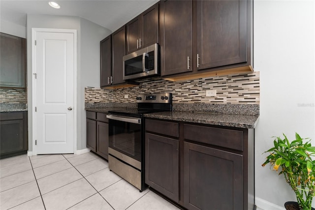 kitchen with light tile patterned flooring, dark brown cabinetry, appliances with stainless steel finishes, and dark stone counters