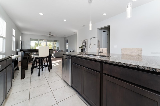 kitchen featuring light stone counters, stainless steel dishwasher, decorative light fixtures, and sink